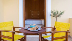 A small room with a bed, a table with a plate of cookies and a cup, and two chairs with yellow cushions. - Louisa's Summer House (Corfu)