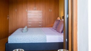 A bedroom with a bed, wooden wardrobe, and a table with two glasses of orange juice and a bowl of croissants. - Louisa's Summer House (Corfu)