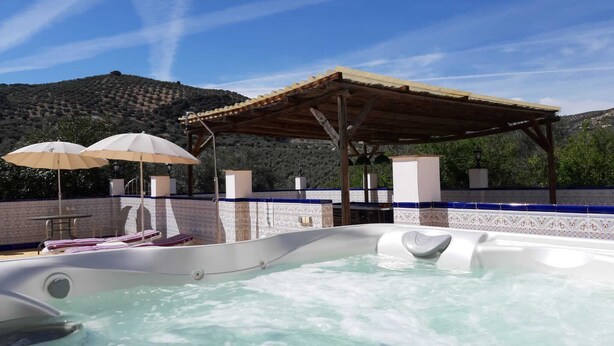 A hot tub area with a pergola, two umbrellas, and a tiled wall. -  Huge Accessible Group Villa ,No Chlorine Pool, Hot Tub Games area,Cinema Room (Iznajar Cordoba Province)