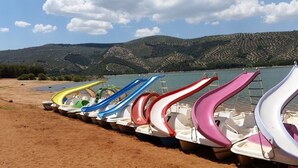 A row of colorful water slides lined up on a sandy beach with a lake and hills in the background. -  Huge Accessible Group Villa ,No Chlorine Pool, Hot Tub Games area,Cinema Room (Iznajar Cordoba Province)