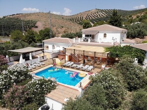 Una villa con piscina, mobiliario de exterior y vistas a las colinas circundantes.