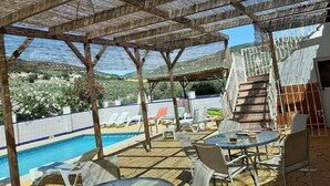 A covered outdoor area with a pool, lounge chairs, and tables. -  Huge Accessible Group Villa ,No Chlorine Pool, Hot Tub Games area,Cinema Room (Iznajar Cordoba Province)