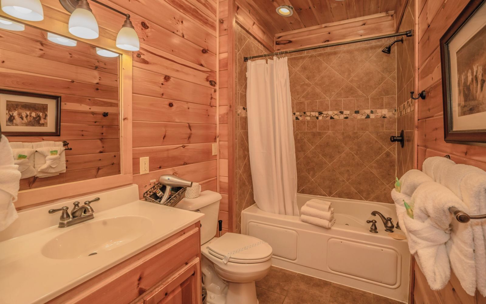 A wooden cabin bathroom with a sink, toilet, bathtub, and shower.