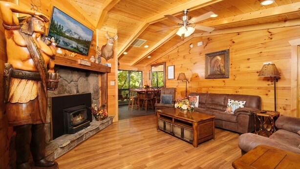 A log cabin interior with a fireplace, wooden furniture, and a dining area. - Traveler's Rest - Hot tub, pool table, and arcade games! (Pigeon Forge)