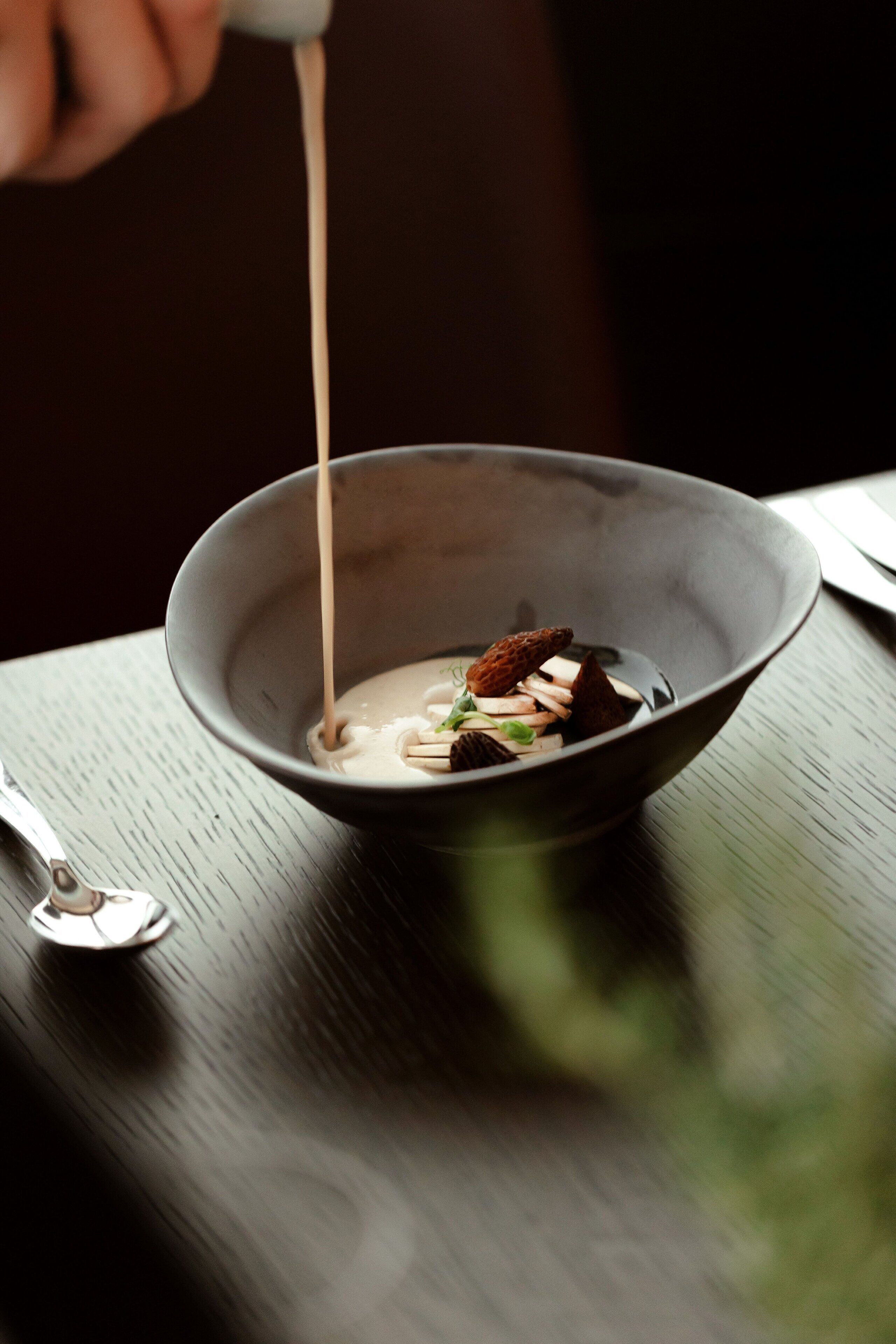 A bowl of food with a spoon on a table.
