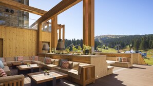 Terraza de madera con mobiliario exterior, incluyendo sofás y mesas, con vistas a un paisaje pintoresco.
