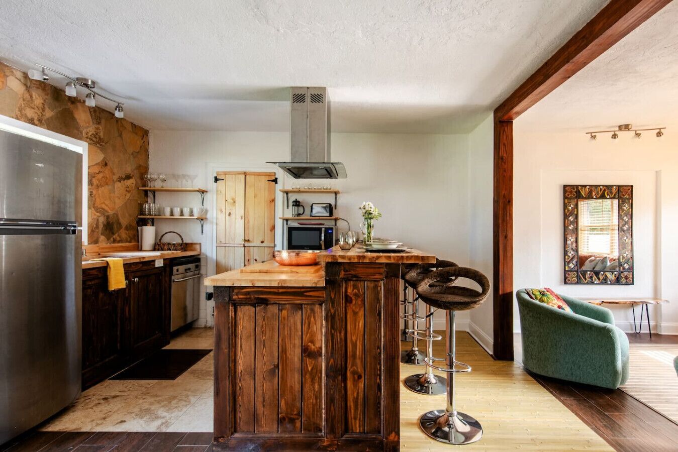 A kitchen with a central island, wooden cabinets, a stainless steel refrigerator, and a microwave.