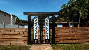 Een houten poort met bloemdecoratieve metalen details, die uitkomt op een pad van baksteen.