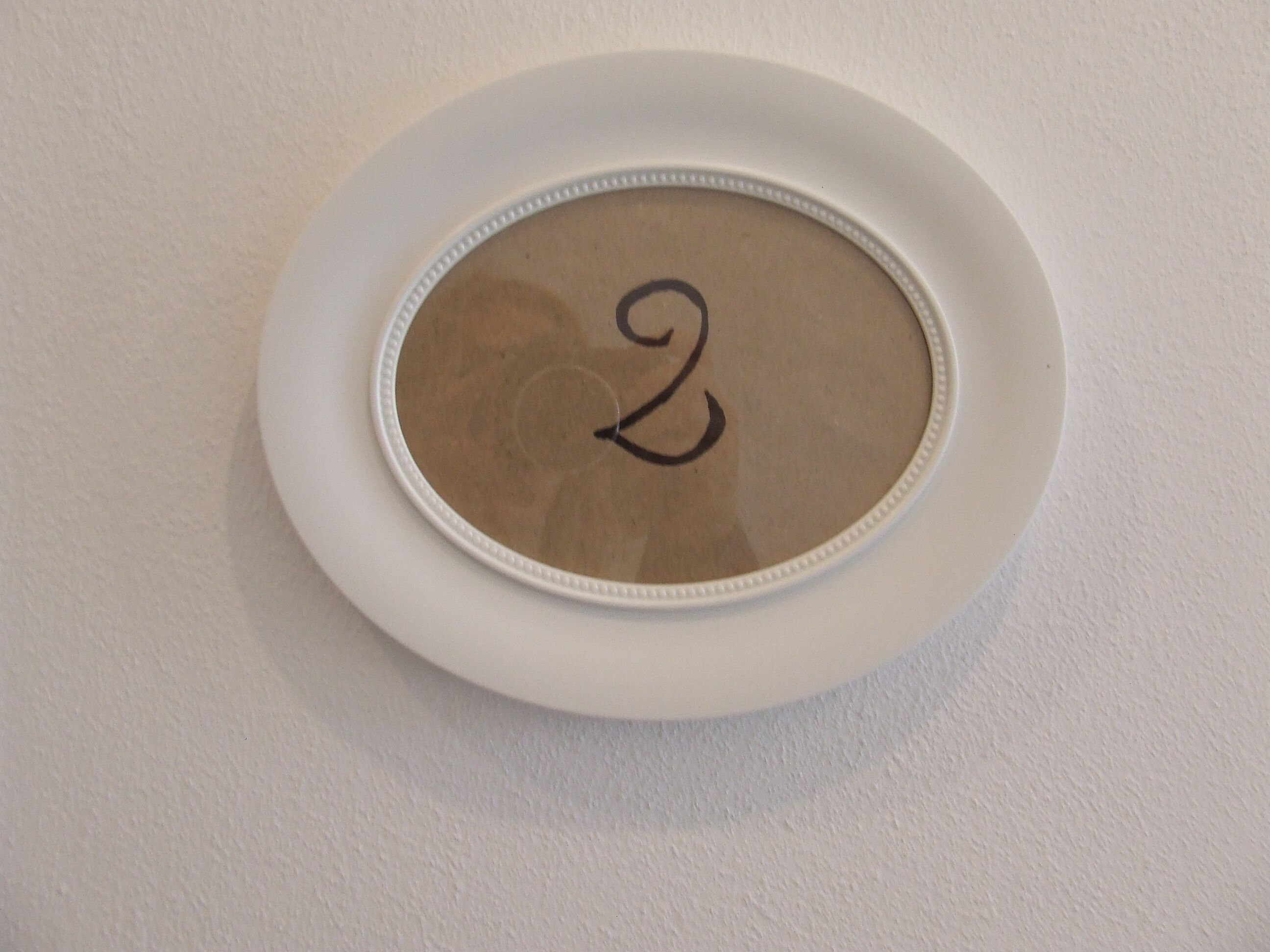 Eine weiße Wand mit einem kreisförmigen Objekt mit der Zahl 2.