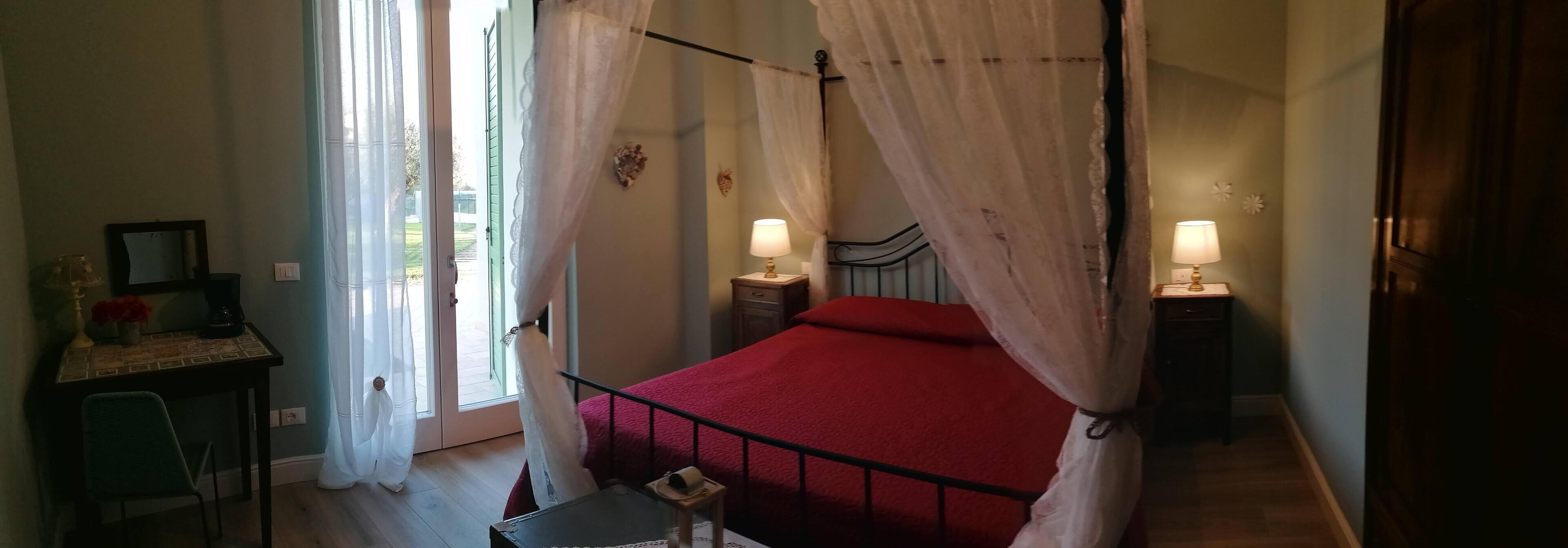 Ein Schlafzimmer mit einem Bett, zwei Nachttischen mit Lampen, einem Schreibtisch mit Stuhl und einem Fenster mit Vorhängen.