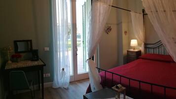 Ein Schlafzimmer mit einem Bett, zwei Nachttischen mit Lampen, einem Schreibtisch mit Stuhl und einem Fenster mit Vorhängen.