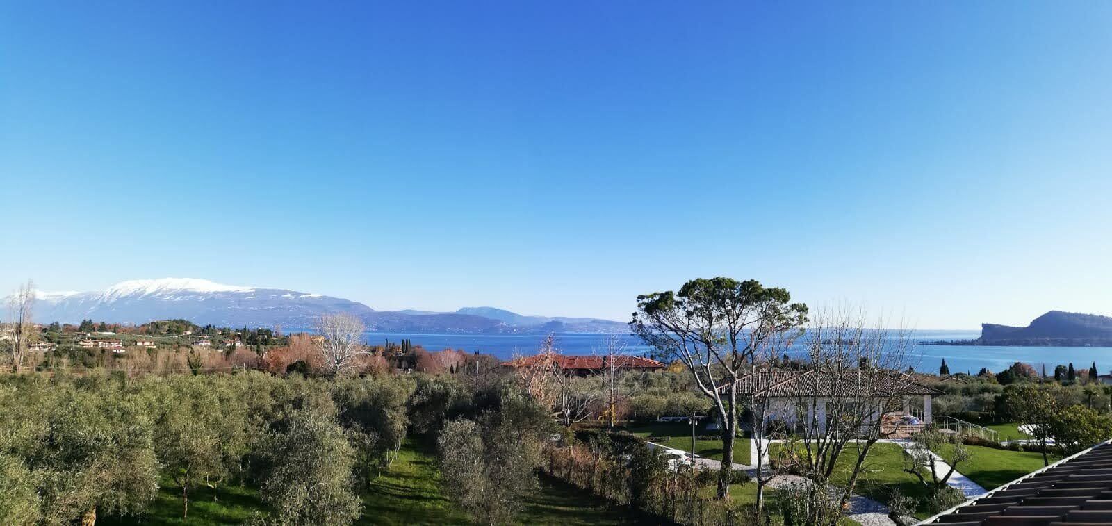 Une vue d’un paysage côtier, avec un ciel dégagé, une étendue d’eau et des montagnes à l’horizon.