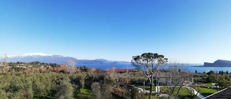 A view of a coastal landscape with a clear sky, a body of water, and distant mountains.