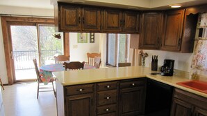 Una cocina con armarios de madera, una encimera y un comedor con sillas y una mesa.
