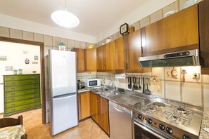 Eine Küche mit Holzschränken, einem Edelstahlkühlschrank, einer Mikrowelle und einem Gasherd.