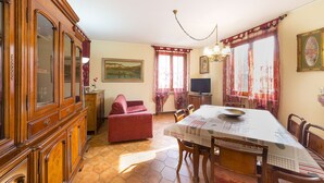 Un comedor con mesa de madera, sillas, sofá rojo y televisor.
