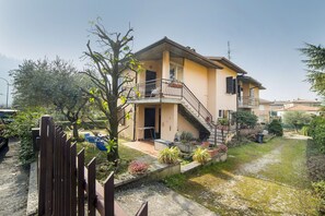A two-story house with a balcony, a staircase, and a small garden area.