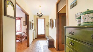 Un pasillo con un banco de madera, un aparador verde con tiradores decorativos y un suelo de patrón hexagonal.