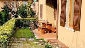 Una propiedad residencial con un camino pavimentado, una mesa y bancos de madera al aire libre y un jardín bien cuidado.