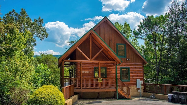 Une cabane en bois dotée d’un porche, portant l’inscription « Sanctuaire », et entourée d’une végétation luxuriante.