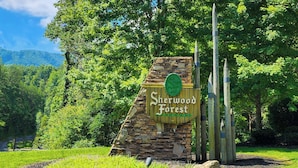 Une pancarte en pierre portant l’inscription « Sherwood Forest Resort », entourée de verdure et d’arbres.