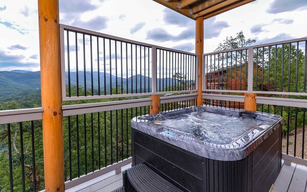 A hot tub on a wooden deck with a view of mountains. - Point of Grace - Private Indoor Pool, hot tub, theater room, game room, mountain views, & more! (Pigeon Forge)
