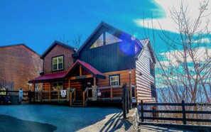 A log cabin-style building with a red roof and a sign reading "Point of Grace." - Point of Grace - Private Indoor Pool, hot tub, theater room, game room, mountain views, & more! (Pigeon Forge)