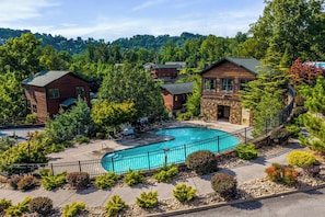 Ein Resort mit Swimmingpool, umgeben von einer Steinterrasse, Holzhäusern und üppiger Vegetation.