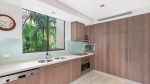 Eine moderne Küche mit großem Fenster, Holzschränken, Backofen und Geschirrspüler.
