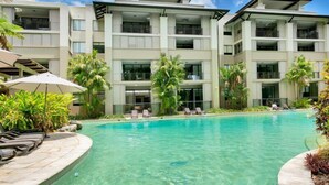 Ein modernes Hotel mit Pool, mehreren Balkonen und tropischer Bepflanzung.