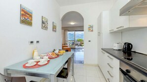 A modern kitchen with a dining area, featuring a kitchen island, a coffee machine, and a view of the outdoors. - DesenzanoLoft Ciao Lago  (Desenzano del Garda)