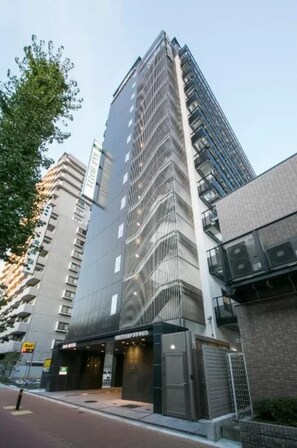 Un edificio moderno de gran altura con una fachada de vidrio destacada y una entrada visible a un hotel o espacio comercial.