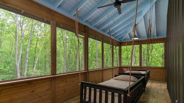 Una cabaña con interior de madera, ventanas amplias y un ventilador de techo.