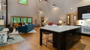 Un espacio habitable amplio con un sofá grande, una mesa de comedor y una cocina con armarios oscuros y una estufa blanca.