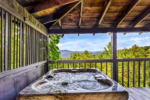 Ein Whirlpool unter einer Hollaube mit Blick auf Berge und Bäume.