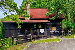 Une cabane rustique avec une cheminée en pierre, un toit rouge et une pancarte indiquant qu’il s’agit d’une cabane offrant une vue panoramique.