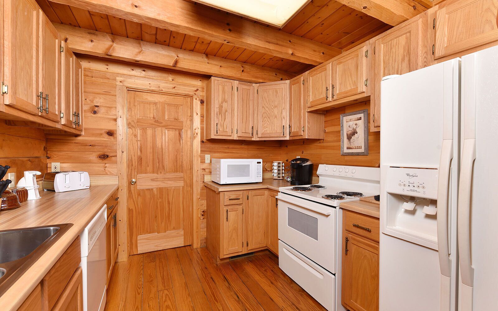 A compact kitchen with wooden cabinets, a microwave, a stove, and a refrigerator.