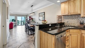 Una cucina moderna con mobili in legno, un piano di lavoro nero e una lavastoviglie in acciaio inossidabile.