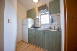 Compact kitchen with oven, sink, and window above the countertop.