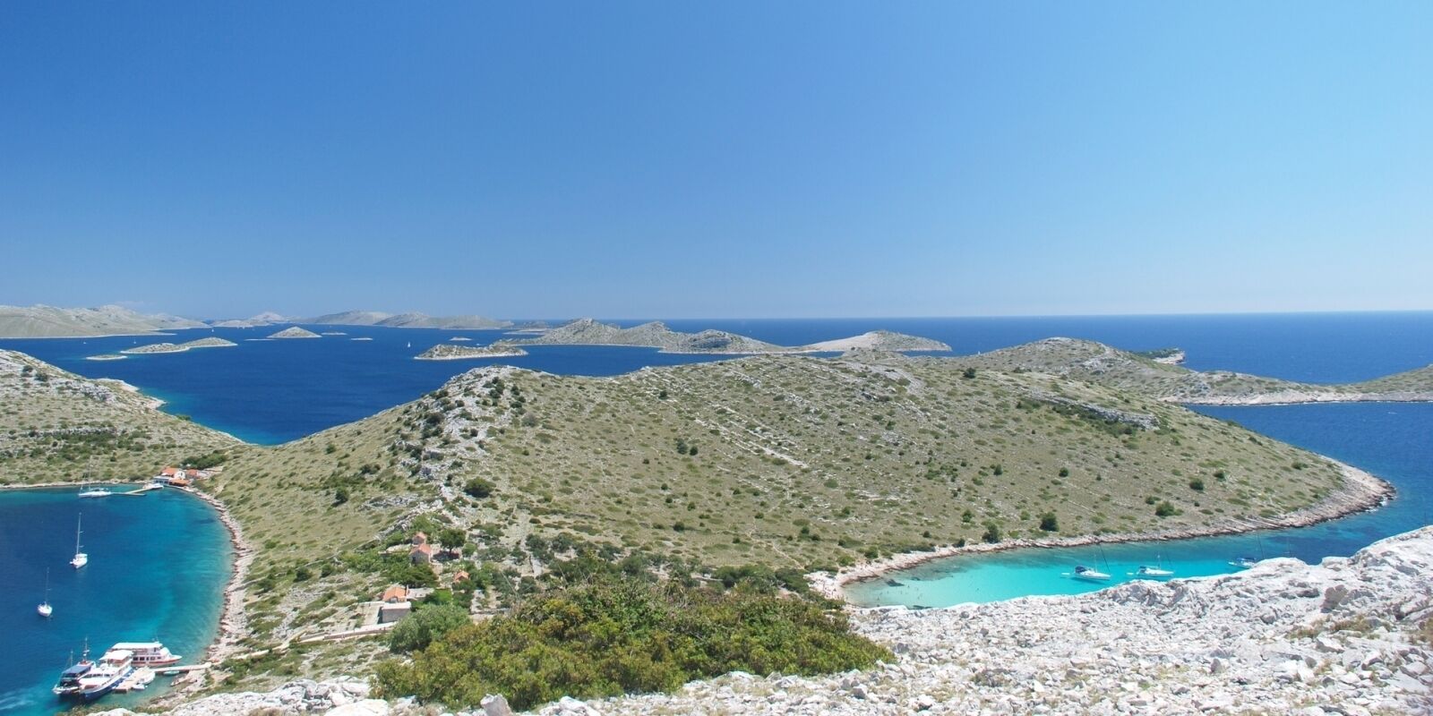 Eine Küstenlandschaft mit felsigem Gelände, klarem, blauem Wasser und vereinzelten Gebäuden.