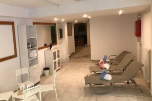 A room with a reception desk, a waiting area with lounge chairs, and a hallway leading to another room.