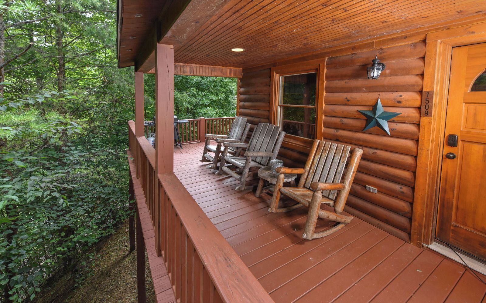 Una cabaña de madera con un porche que tiene mecedoras y una decoración con forma de estrella.