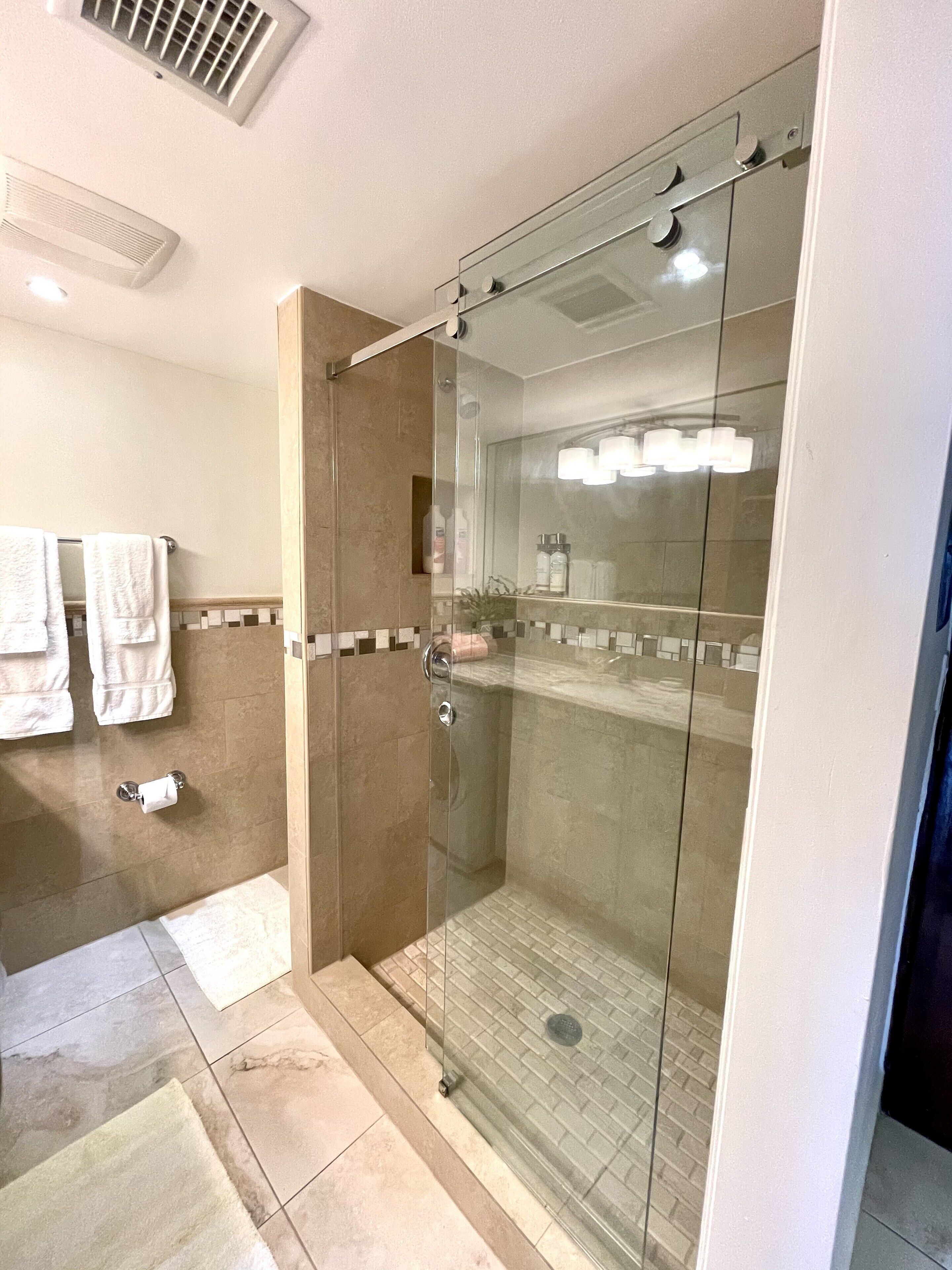 A modern bathroom with a glass-enclosed shower, a toilet, and a sink.
