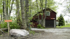 Une cabane rustique avec une façade en bois, un garage et une enseigne indiquant son nom.