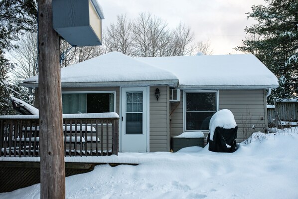 Una casa cubierta de nieve, con puerta principal y ventanas visibles.
