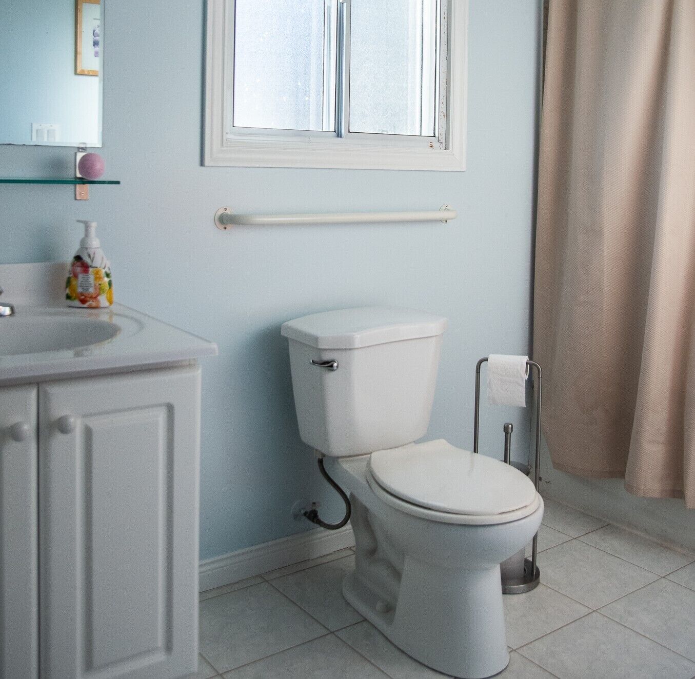 Ein Badezimmer mit Toilette, Waschbecken, Spiegel und Fenster.
