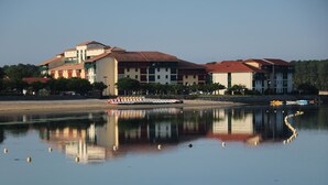 Un hôtel situé au bord de l’eau, composé de plusieurs bâtiments, avec un quai où est amarré un bateau, et des eaux calmes qui reflètent les structures environnantes.