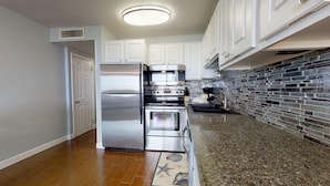 A kitchen with stainless steel appliances, white cabinets, and a granite countertop. - Meticulously Decorated Gulf Front Unit at Jetty East! One FREE Beach Chair Setup (Destin)