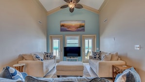 A living room with two sofas, a TV, and a ceiling fan. - Decked Out - Newly Renovated Four-Bedroom, Two-Bath Oceanfront Beach House (Garden City Beach)