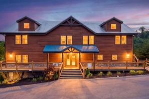 A two-story wooden building with a porch, a staircase leading to the entrance, and a metal roof. - Mountain View, Private Pool, Theater Room, Hot Tub, & more! - Big Forest Lodge (Sevierville)